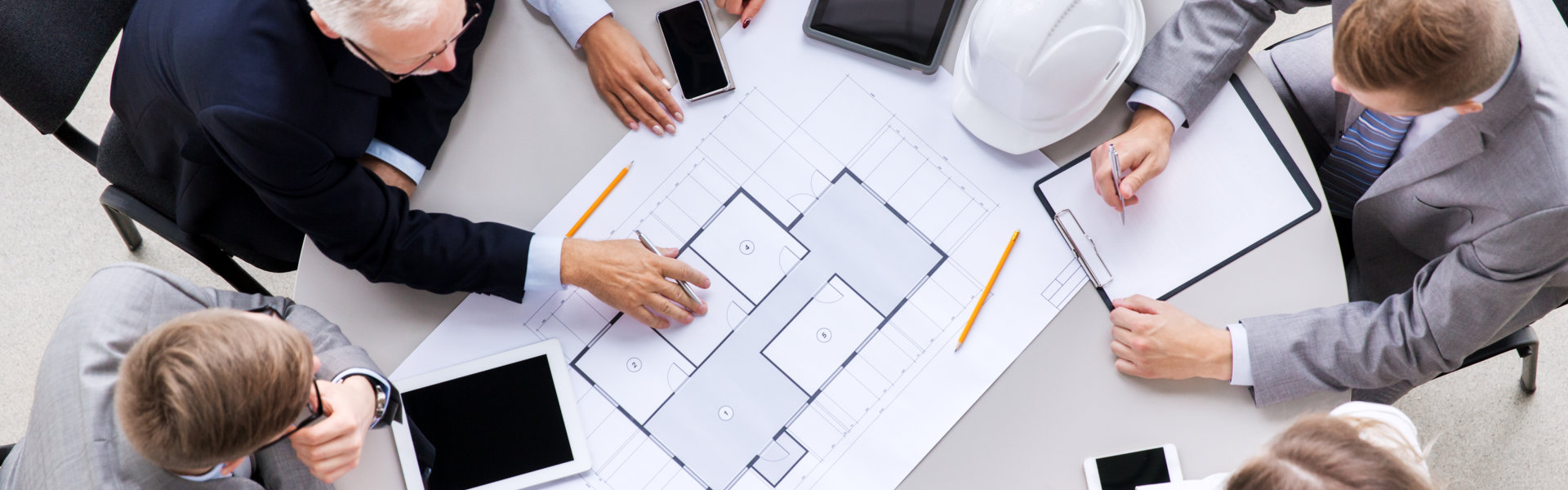 construction business, architecture and building concept - group of architects with laptop computer discussing blueprint at office